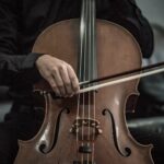person wearing black dress shirt playing brown cello string instrument